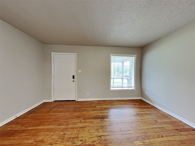 spare room with a textured ceiling and light hardwood / wood-style flooring