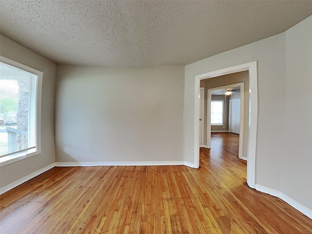 empty room featuring a textured ceiling, plenty of natural light, and light wood-type flooring