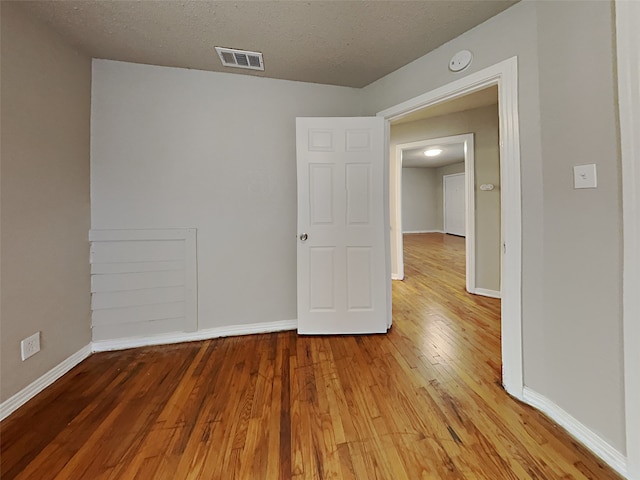 unfurnished room featuring wood-type flooring and a textured ceiling