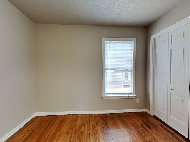 unfurnished bedroom with a closet, hardwood / wood-style floors, and a textured ceiling