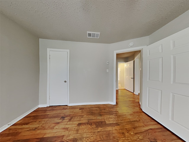 unfurnished bedroom featuring hardwood / wood-style floors and a textured ceiling