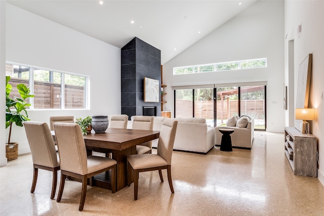 dining space with a fireplace and high vaulted ceiling