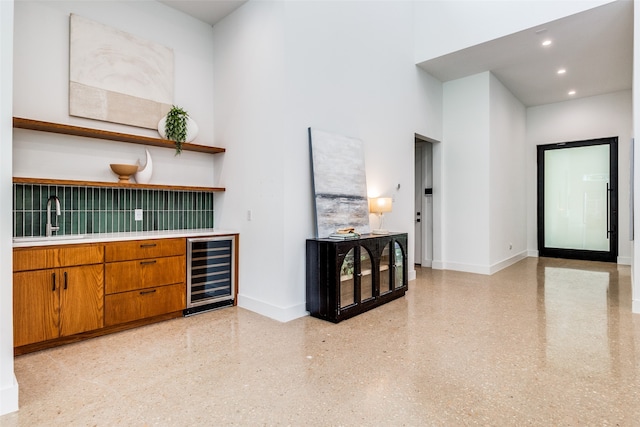 living room with sink, a high ceiling, and beverage cooler