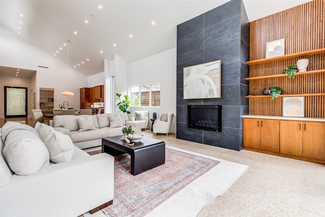 living room with sink, a tile fireplace, high vaulted ceiling, and tile walls