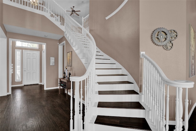 staircase with a high ceiling, ceiling fan, and hardwood / wood-style flooring