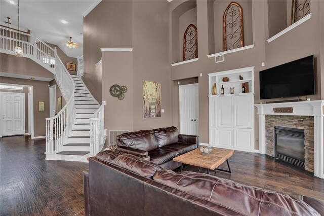 living room with built in shelves, ceiling fan, dark hardwood / wood-style floors, a high ceiling, and a fireplace