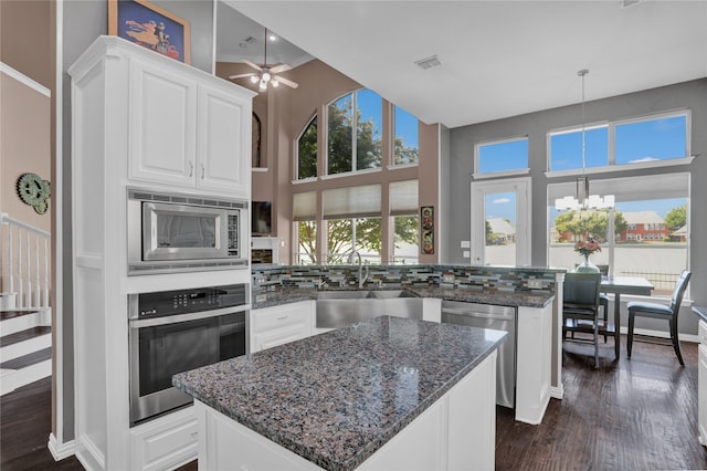 kitchen featuring white cabinets, a kitchen island, stainless steel appliances, backsplash, and ceiling fan