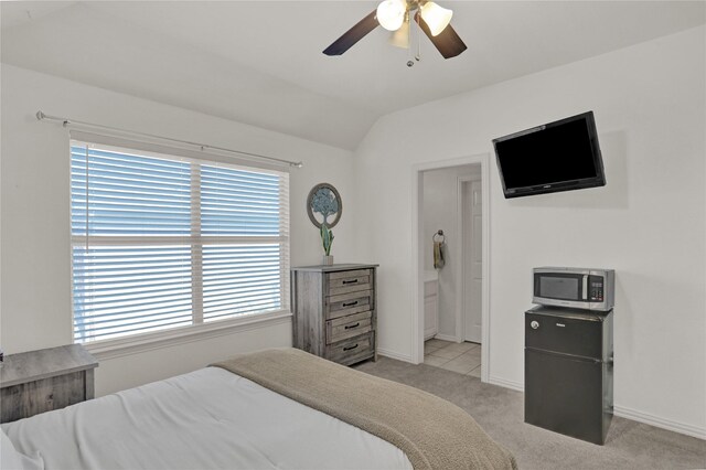 bedroom featuring ceiling fan, light colored carpet, lofted ceiling, and ensuite bath