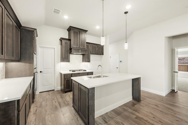 kitchen featuring hardwood / wood-style floors, lofted ceiling, backsplash, sink, and decorative light fixtures