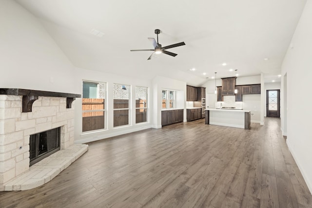 unfurnished living room featuring a fireplace, ceiling fan, dark hardwood / wood-style flooring, and lofted ceiling