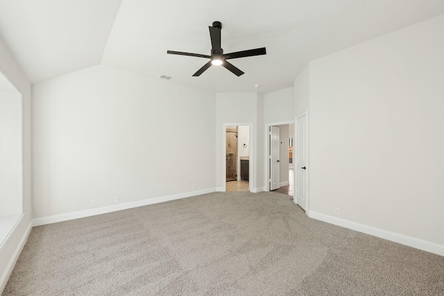 carpeted spare room featuring vaulted ceiling and ceiling fan