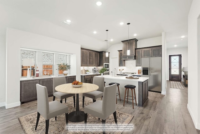 dining space featuring light wood-type flooring, sink, and vaulted ceiling