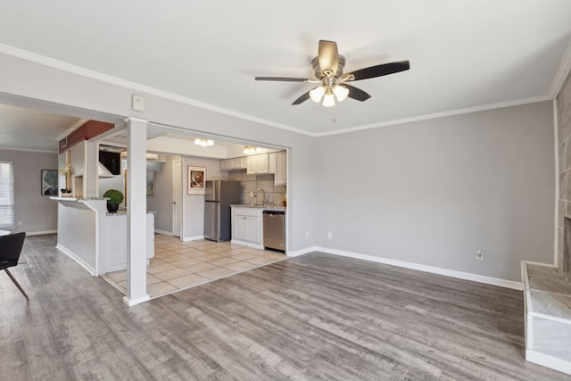 unfurnished living room with light wood-type flooring, ceiling fan, ornamental molding, and sink