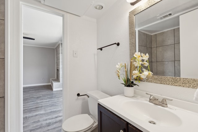 bathroom with toilet, hardwood / wood-style flooring, crown molding, and vanity