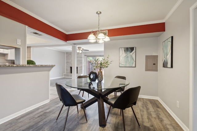 dining room featuring electric panel, a tile fireplace, crown molding, ceiling fan with notable chandelier, and wood-type flooring