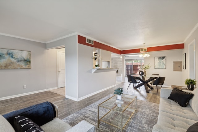 living room featuring an inviting chandelier, ornamental molding, and hardwood / wood-style flooring