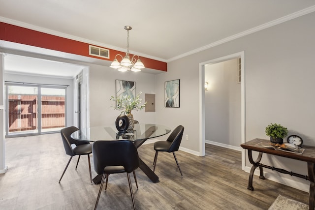 dining room with wood-type flooring, a chandelier, electric panel, and crown molding