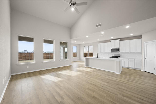 unfurnished living room with high vaulted ceiling, light hardwood / wood-style floors, sink, and ceiling fan