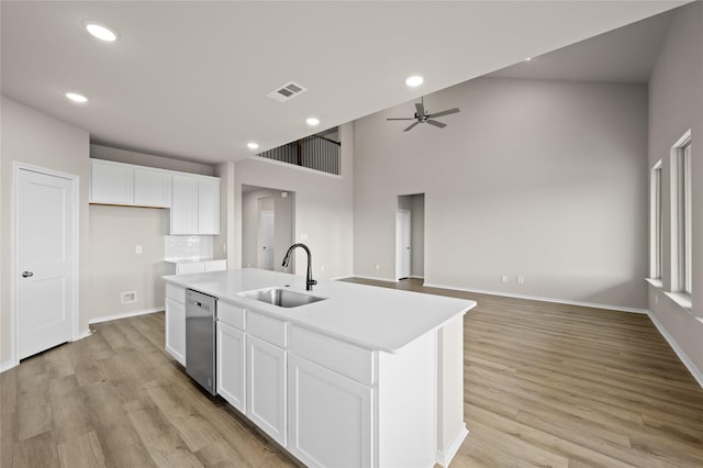 kitchen featuring sink, white cabinets, dishwasher, and an island with sink