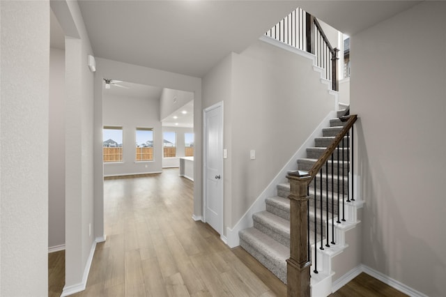 stairway with ceiling fan and wood-type flooring