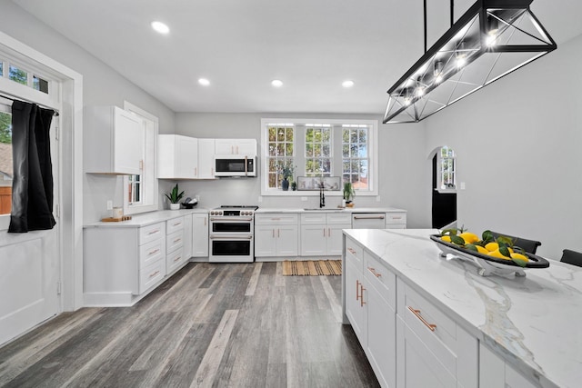 kitchen featuring sink, white appliances, light stone counters, white cabinets, and decorative light fixtures