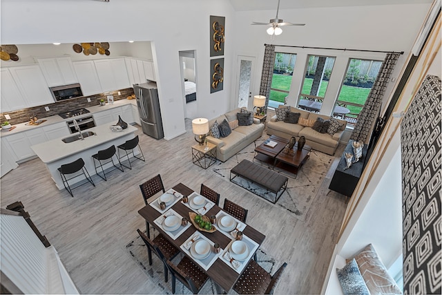 living room featuring ceiling fan, light wood-type flooring, and high vaulted ceiling