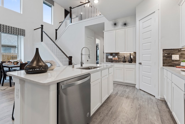 kitchen featuring a high ceiling, a center island with sink, white cabinetry, and stainless steel dishwasher