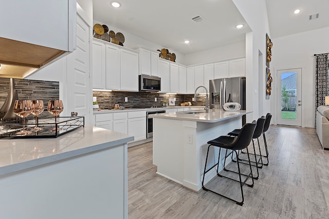 kitchen featuring a kitchen bar, white cabinets, stainless steel appliances, and sink