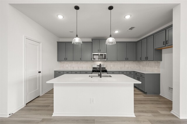 kitchen with light hardwood / wood-style flooring, white cabinetry, a center island with sink, and appliances with stainless steel finishes