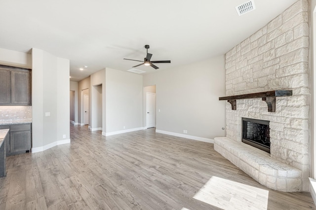 unfurnished living room featuring ceiling fan, light wood-type flooring, and a fireplace