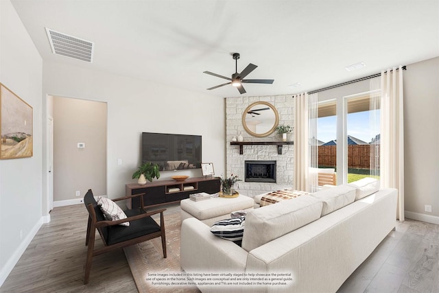 living room featuring ceiling fan, wood-type flooring, and a fireplace