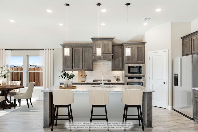 kitchen with stainless steel fridge with ice dispenser, hanging light fixtures, and an island with sink