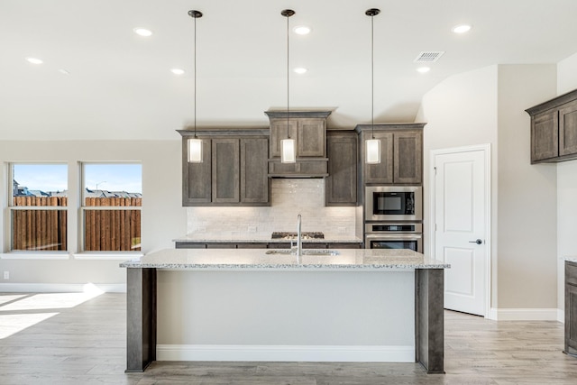 kitchen featuring light stone counters, pendant lighting, and light hardwood / wood-style floors