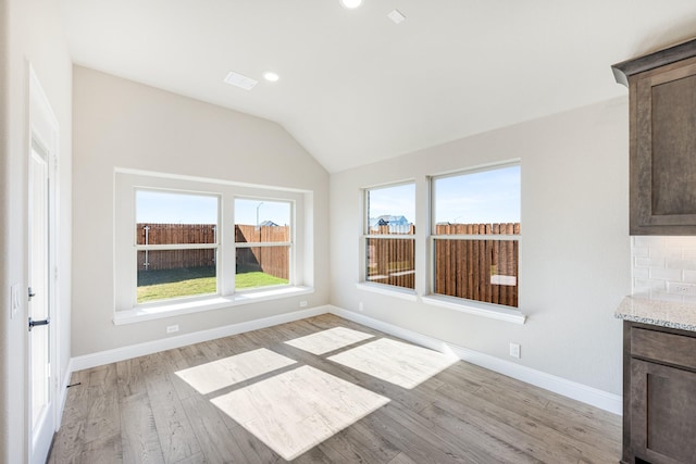 interior space with light wood-type flooring and vaulted ceiling