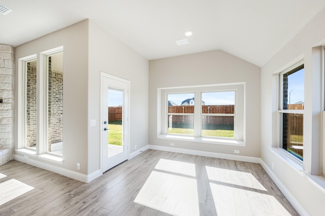 interior space featuring light wood-type flooring, vaulted ceiling, and plenty of natural light