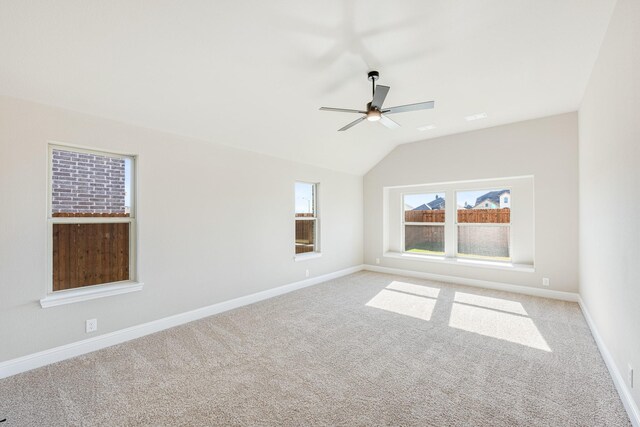 empty room featuring ceiling fan, lofted ceiling, and light carpet