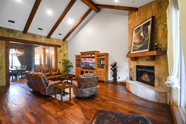 living room with beamed ceiling, dark hardwood / wood-style flooring, a notable chandelier, and a stone fireplace