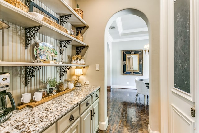 bar with dark wood-type flooring, light stone countertops, and crown molding