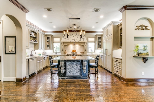 kitchen with backsplash, a kitchen island, a breakfast bar area, light stone counters, and paneled built in refrigerator