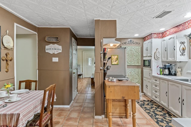 kitchen featuring light tile patterned floors, built in microwave, sink, and white cabinetry