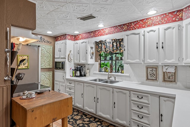 kitchen with white cabinetry, decorative backsplash, sink, stainless steel refrigerator, and built in microwave