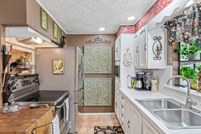 kitchen featuring tasteful backsplash, electric range, sink, light tile patterned floors, and white cabinets