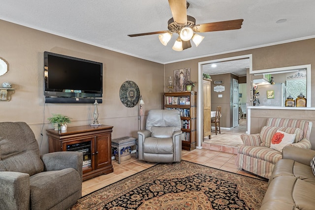 tiled living room featuring ceiling fan, a textured ceiling, and ornamental molding