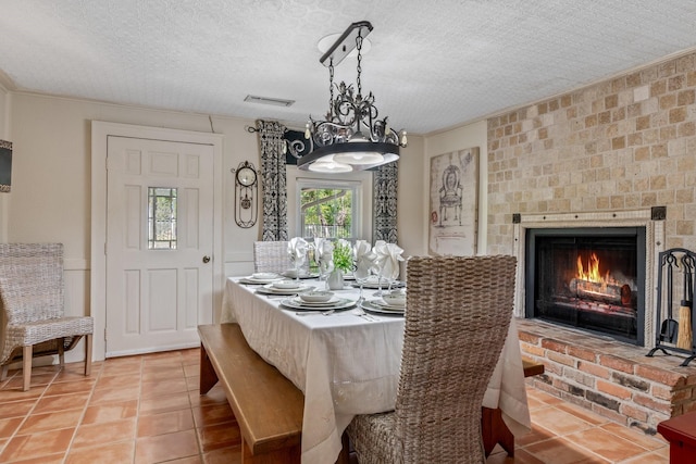 tiled dining space featuring a textured ceiling, ornamental molding, and a fireplace