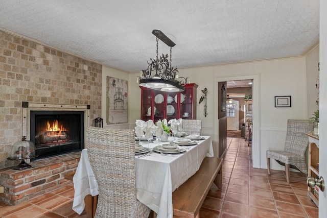 dining area featuring a textured ceiling, a large fireplace, crown molding, and tile patterned floors