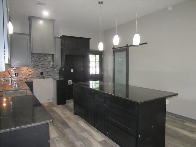 kitchen with sink, hardwood / wood-style floors, tasteful backsplash, a kitchen island, and a barn door