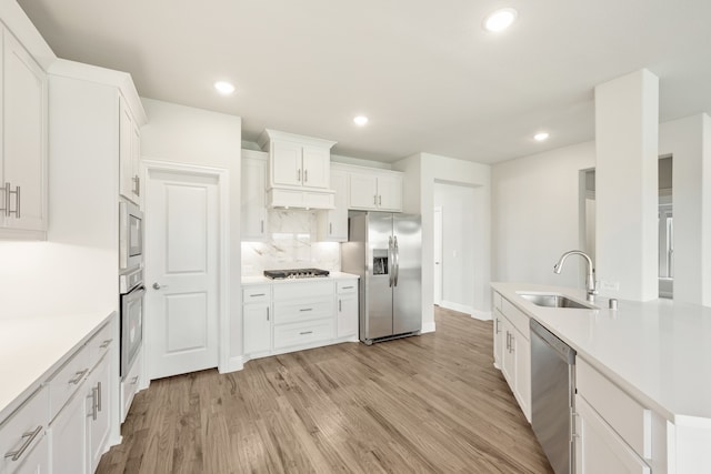 kitchen featuring light hardwood / wood-style flooring, stainless steel appliances, sink, white cabinets, and tasteful backsplash