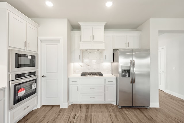 kitchen featuring white cabinetry, stainless steel appliances, tasteful backsplash, and light wood-type flooring