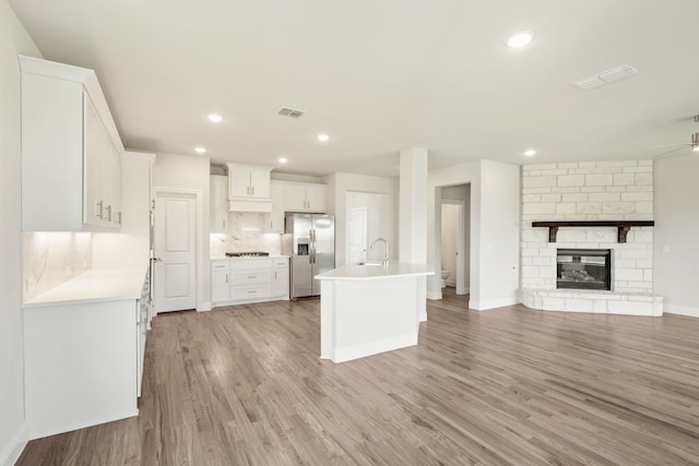 kitchen featuring sink, an island with sink, stainless steel refrigerator with ice dispenser, and light hardwood / wood-style floors