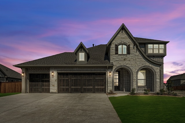 french country style house featuring a lawn and a garage